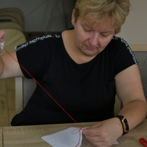Na zdjęciu uczestniczka projektu Haft Kurpi Białych wyszywa wzory kurpiowskie