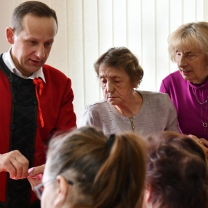 Pan Stanisław Ropiak udziela rad uczestnikom, jak wykonać kwiaty z bibuły